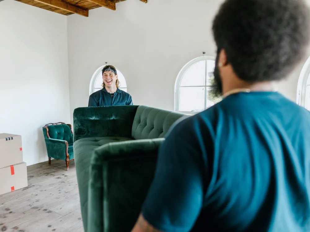 Two movers carrying a sofa in an empty room
