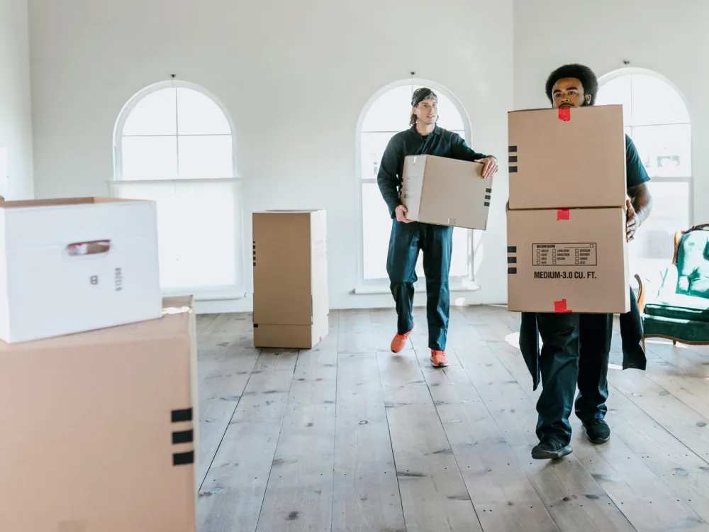Movers carrying packed cartons inside a home