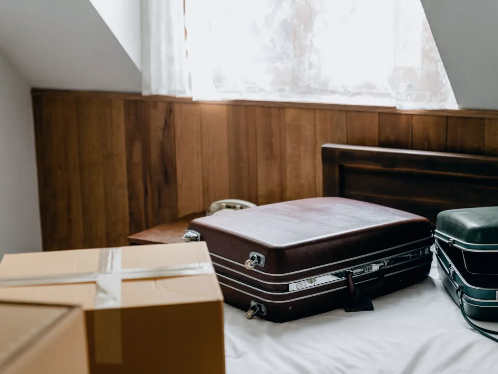 Two suitcases and a sealed carton on a bed