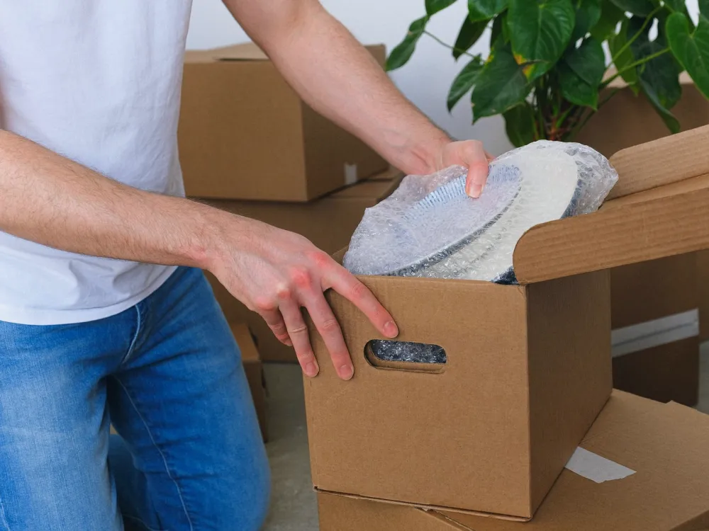 Packing crew wrapping furniture and sealing cartons in a home