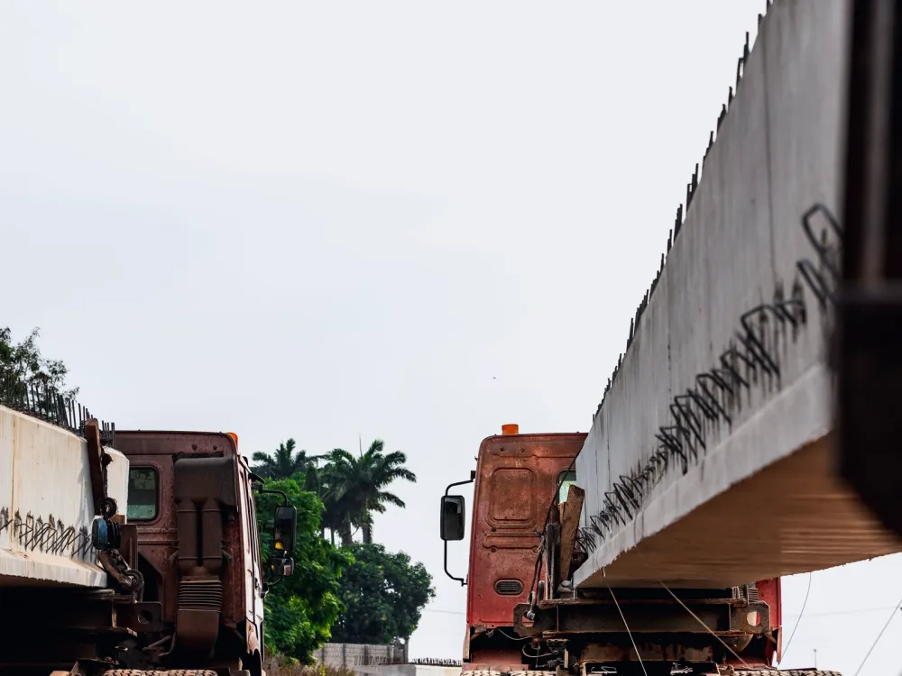 Heavy trucks carrying long concrete beams